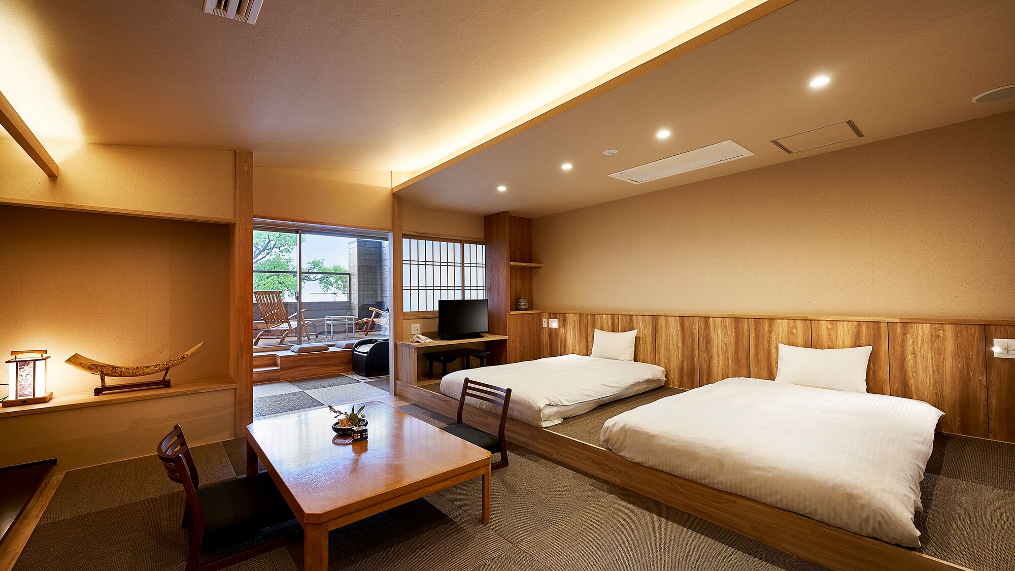 A hotel room with two beds, a desk, a TV, and a balcony with a view.