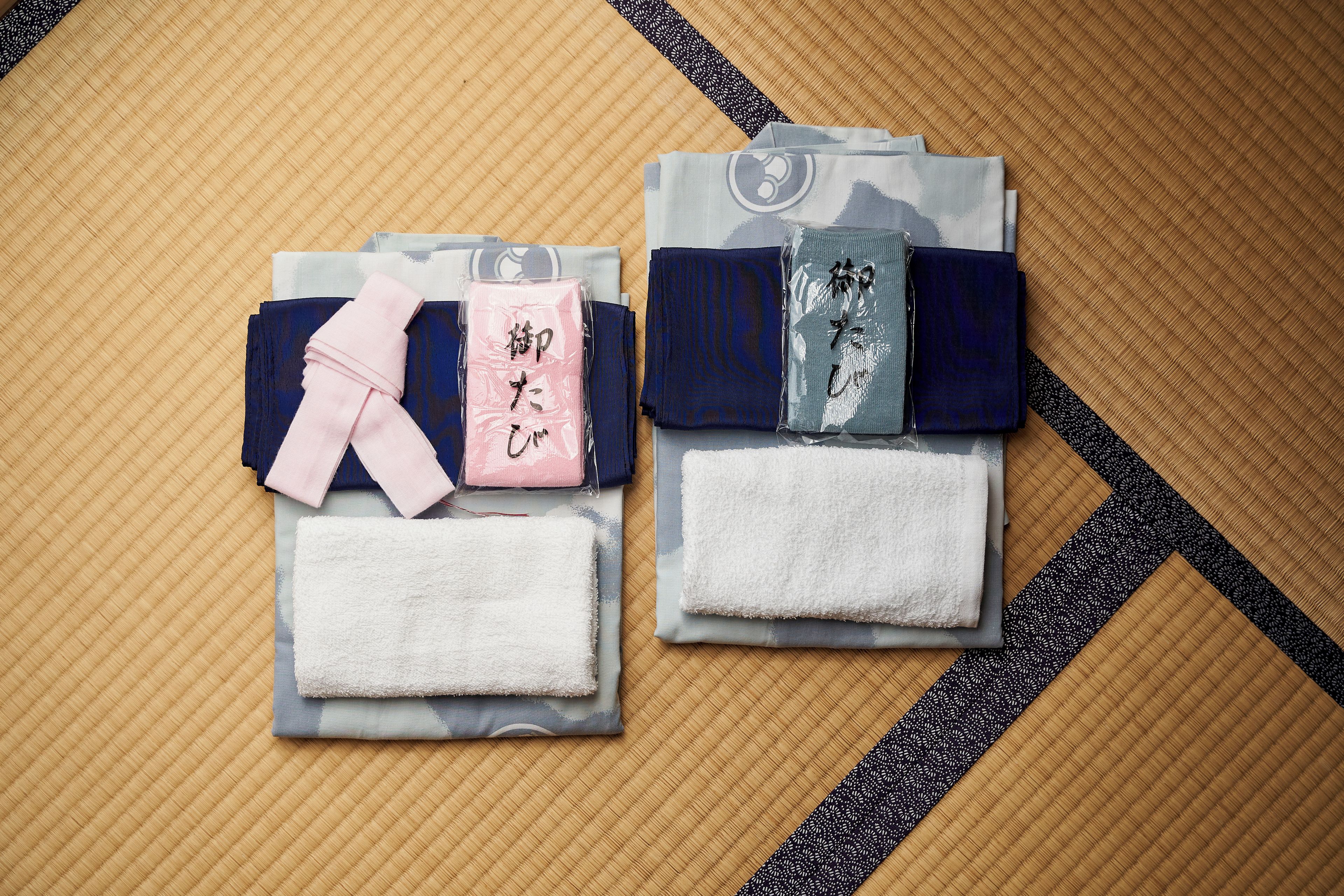 Two packages of Japanese bath towels with a bamboo mat background.
