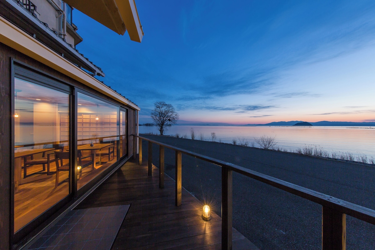 A modern building with a wooden deck overlooking a body of water.