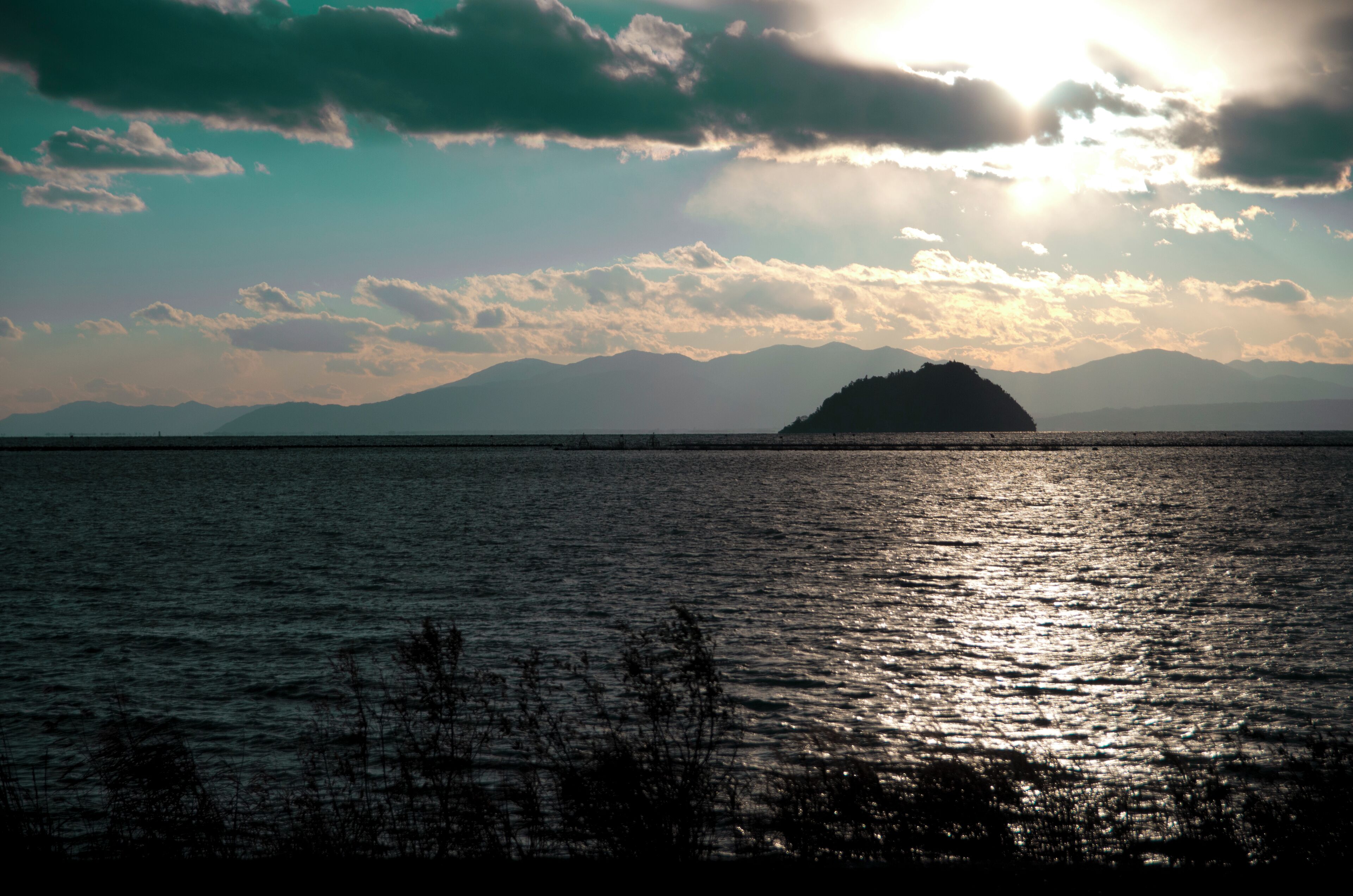 A body of water with a distant landmass and mountains in the background.