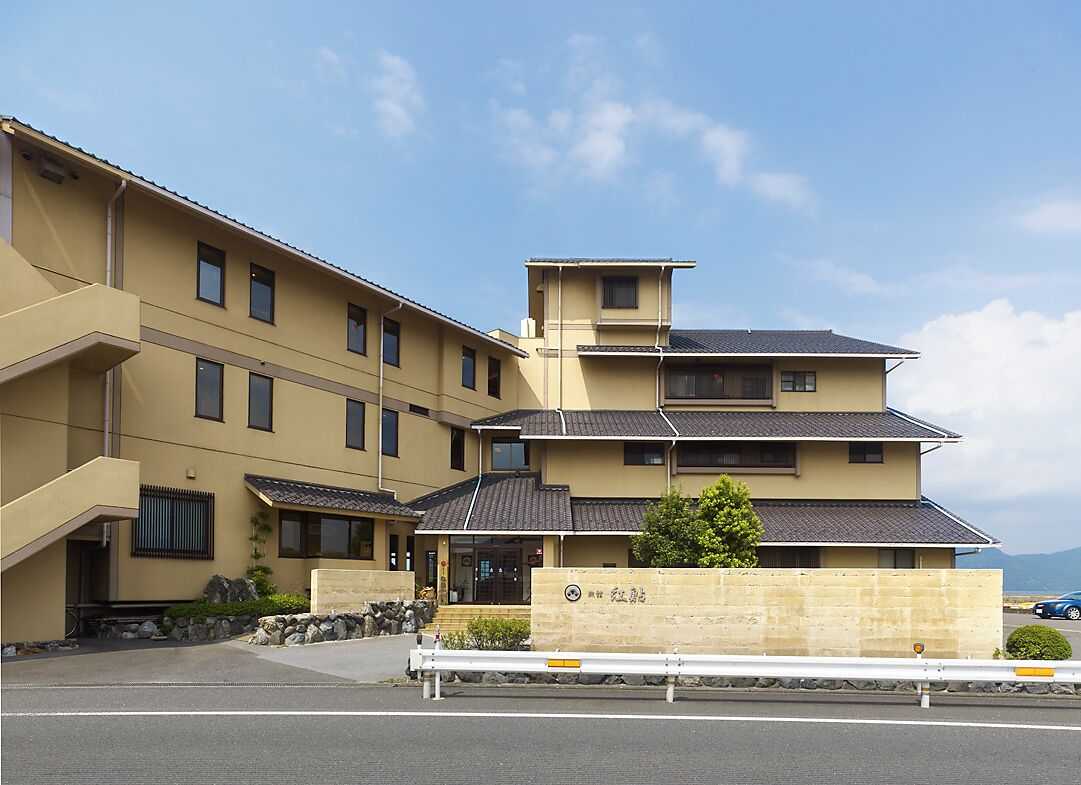 A multi-story building with a flat roof and a stone wall in front.