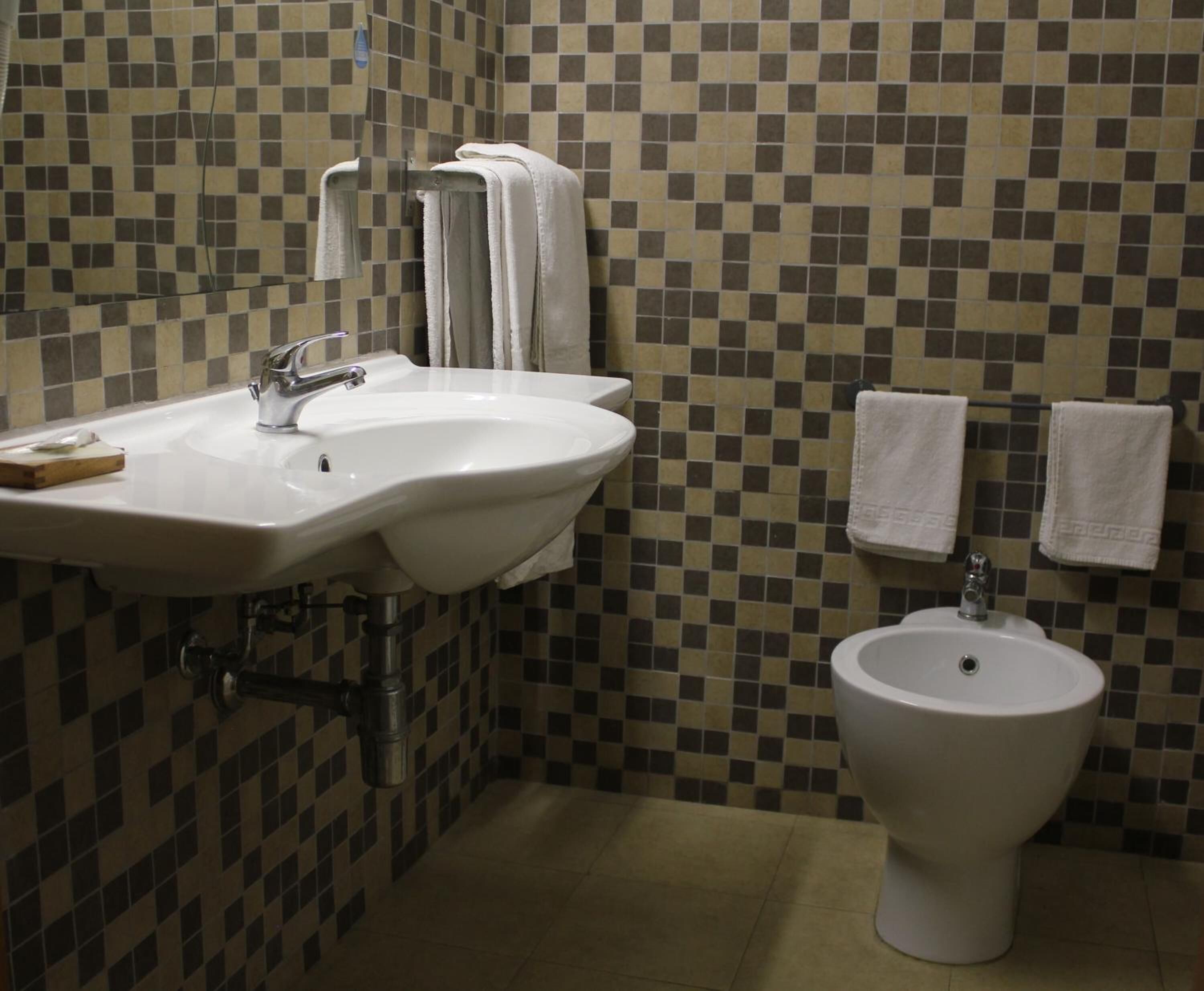 Baño con dos lavamanos, un bidé y paredes con azulejos.
