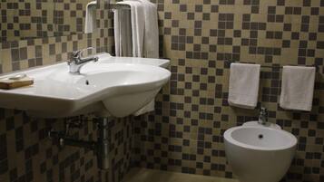 Baño con dos lavamanos, un bidé y paredes con azulejos.