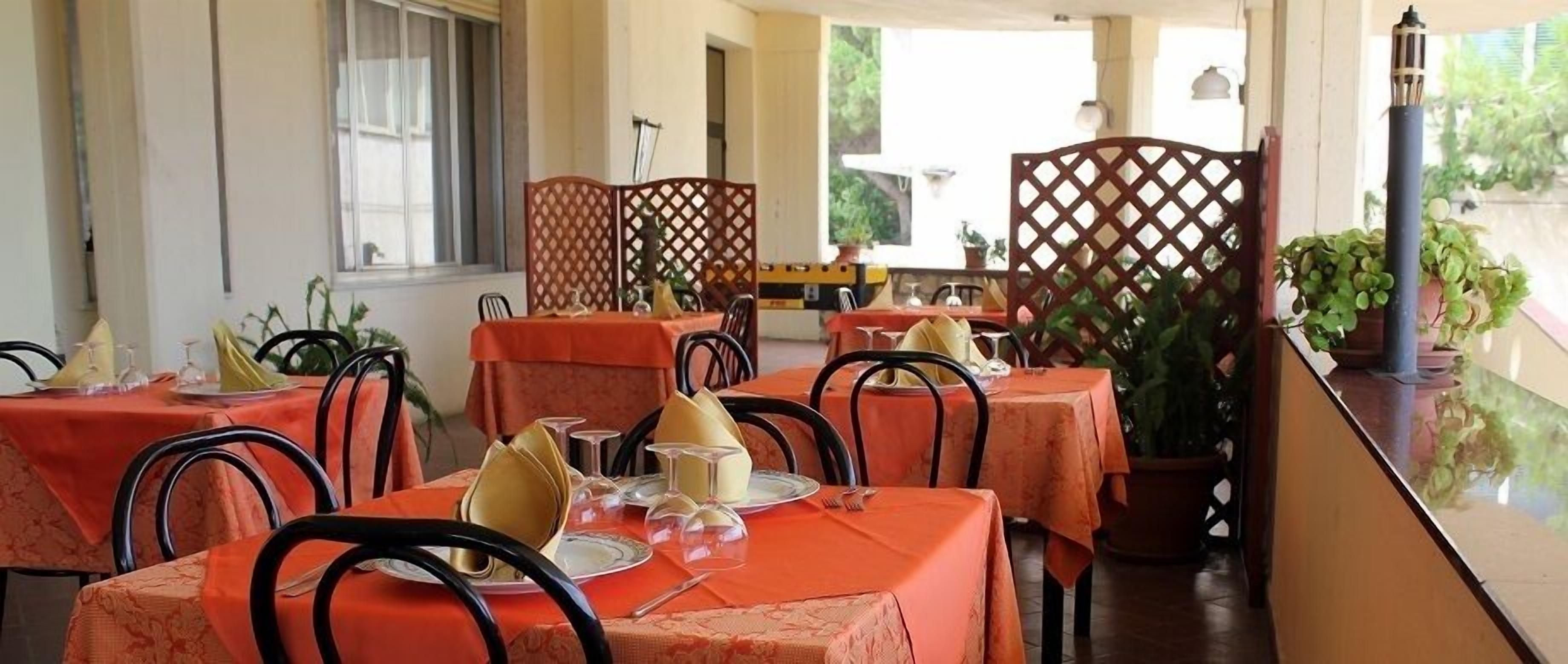 Un ristorante con tavoli apparecchiati per la cena, con vista su piante verdi.