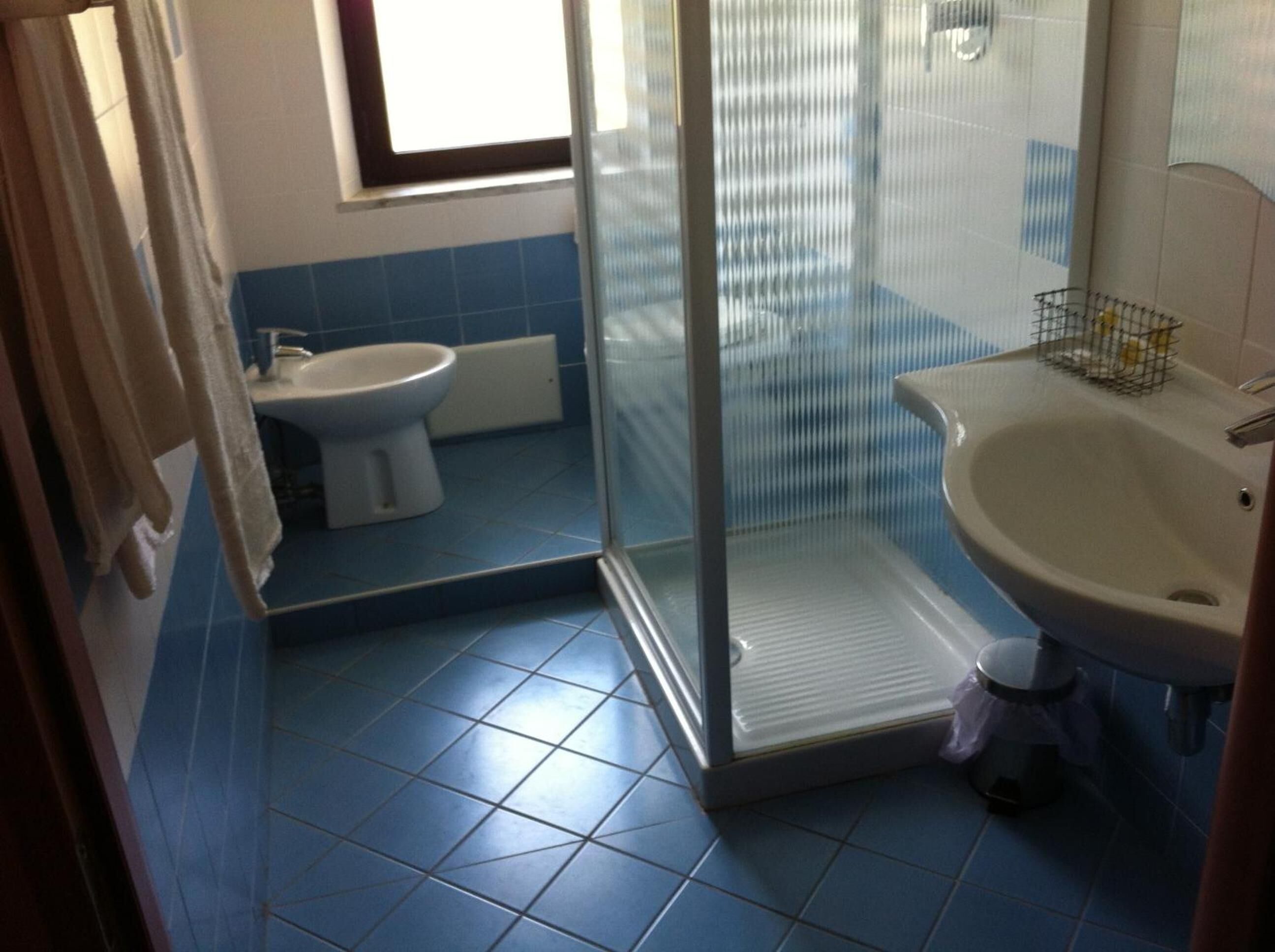 A bathroom with a glass shower enclosure, a toilet, and a sink.
