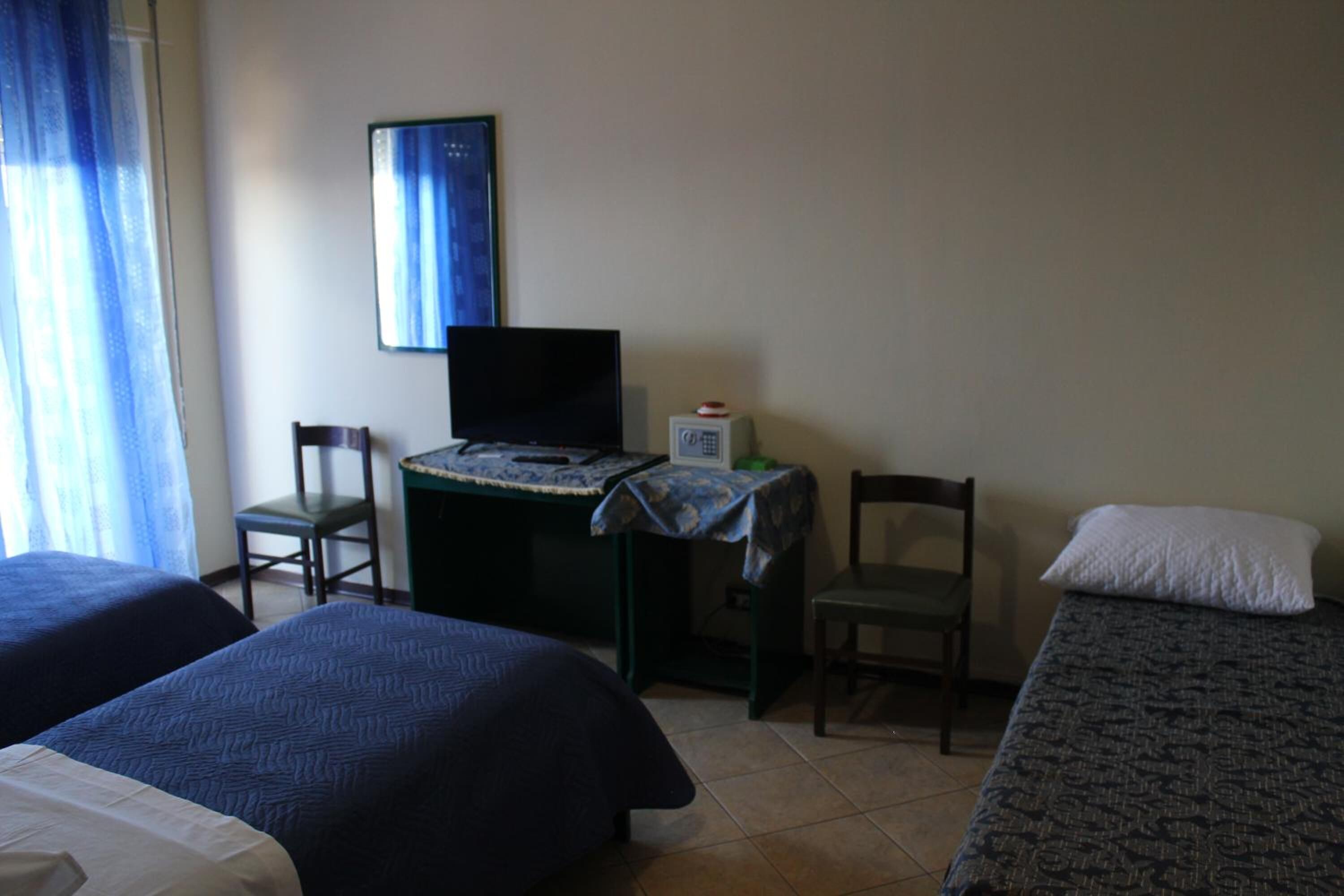 Een hotelkamer met twee bedden, een bureau met een computer, een stoel en een televisie.