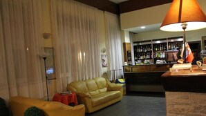 A living room with a yellow sofa, a red table, and a bar area with a lamp.