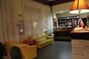 A living room with a yellow sofa, a red table, and a bar area with a lamp.