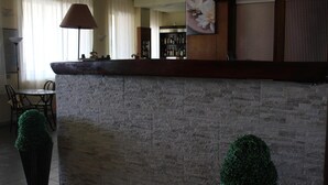 A reception area with a stone wall, a counter, a lamp, a chair, and a potted plant.