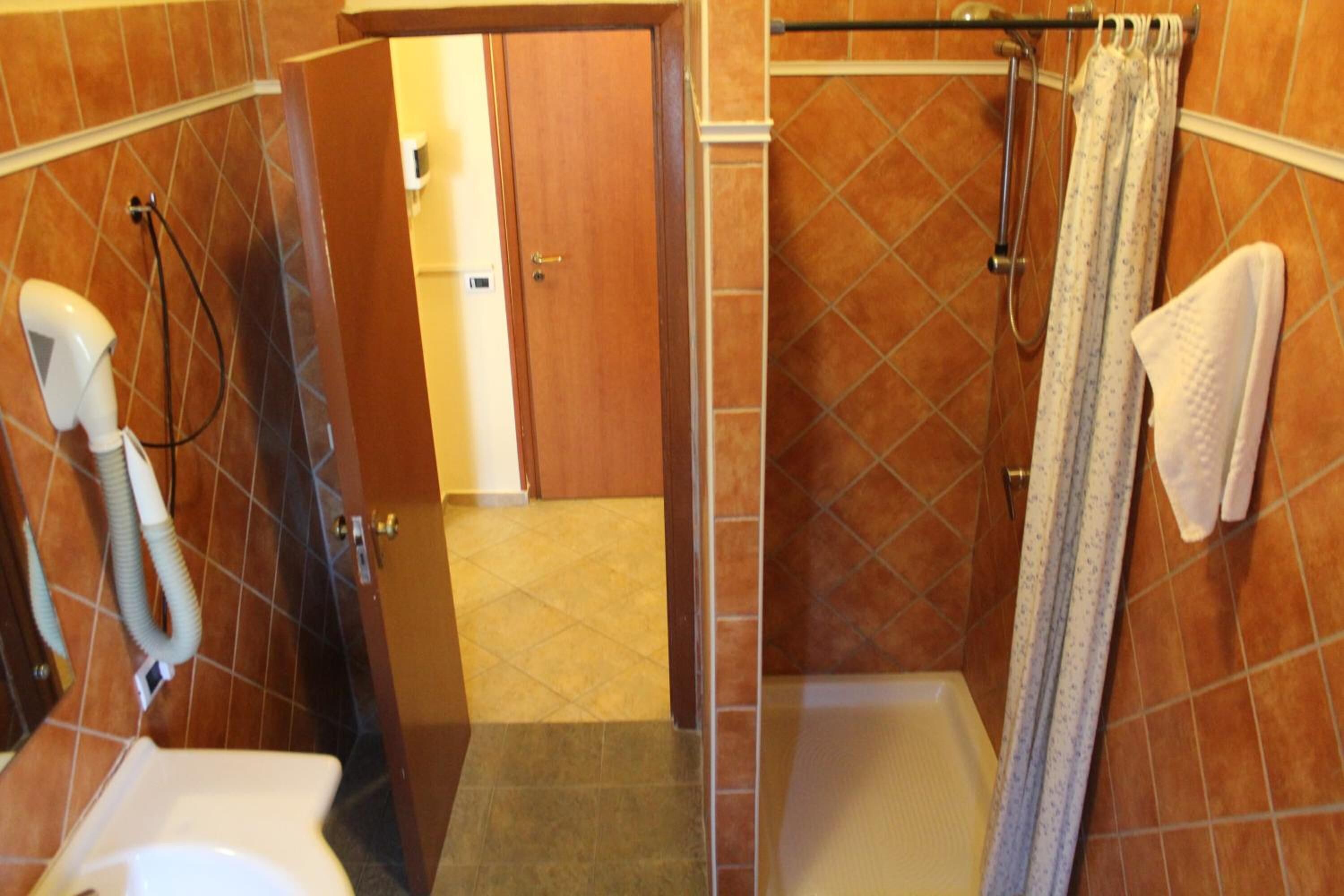 Een badkamer met een douche, toilet en handdoekhouder.