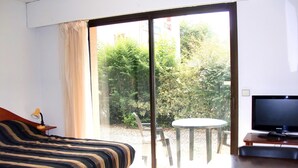 Une chambre d’hôtel avec un lit, un bureau avec une télévision, une chaise et une table placée devant la fenêtre.