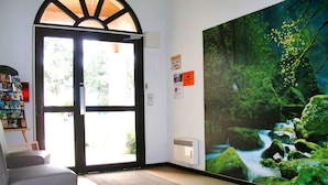 Une pièce dotée d’une grande fenêtre, d’une porte, d’une bibliothèque et d’une affiche représentant un paysage forestier.