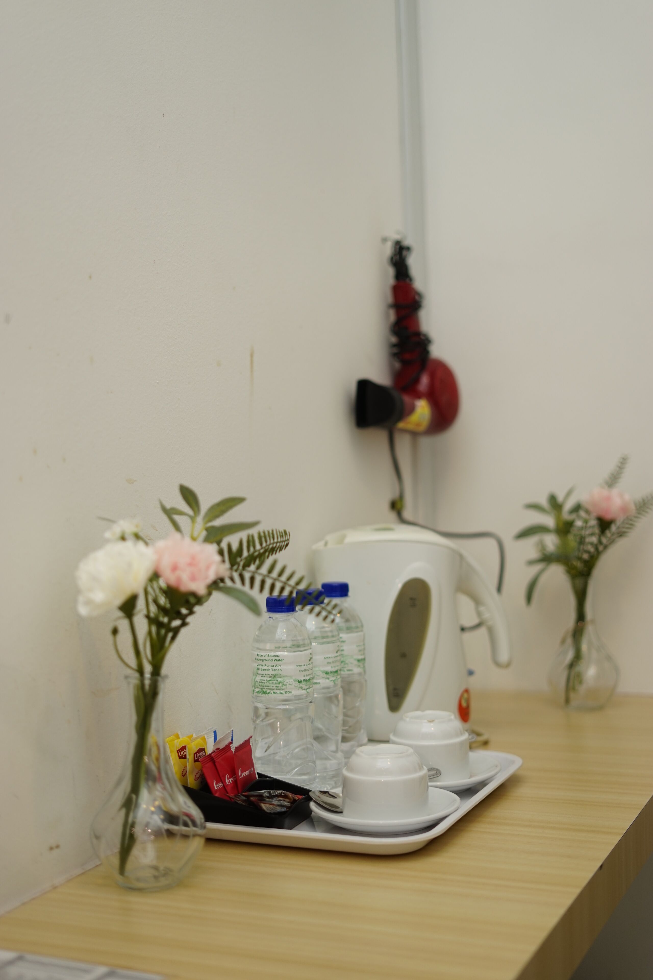 A table with a tea set, a kettle, and a vase with flowers.