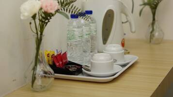 A table with a tea set, a kettle, and a vase with flowers.