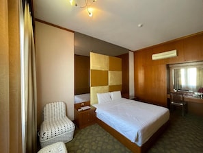 A hotel room with a bed, a chair, a desk, and a mirror. - Swan Garden Hotel (Masai)