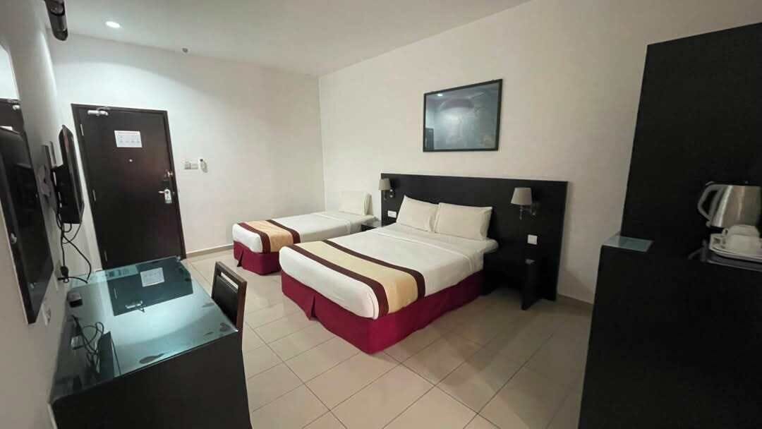 A hotel room with two beds, a desk, a chair, a television, and a coffee maker.