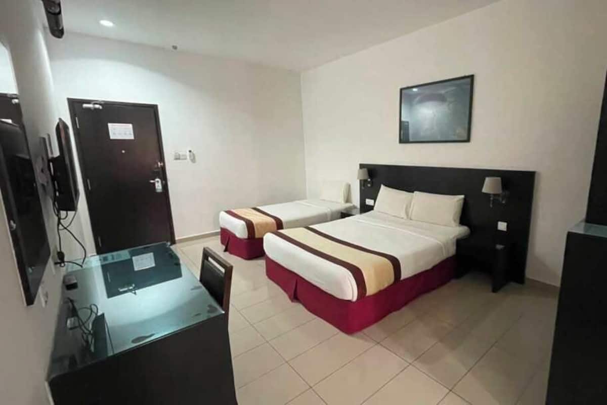 A hotel room with two beds, a desk, a chair, a television, and a coffee maker.