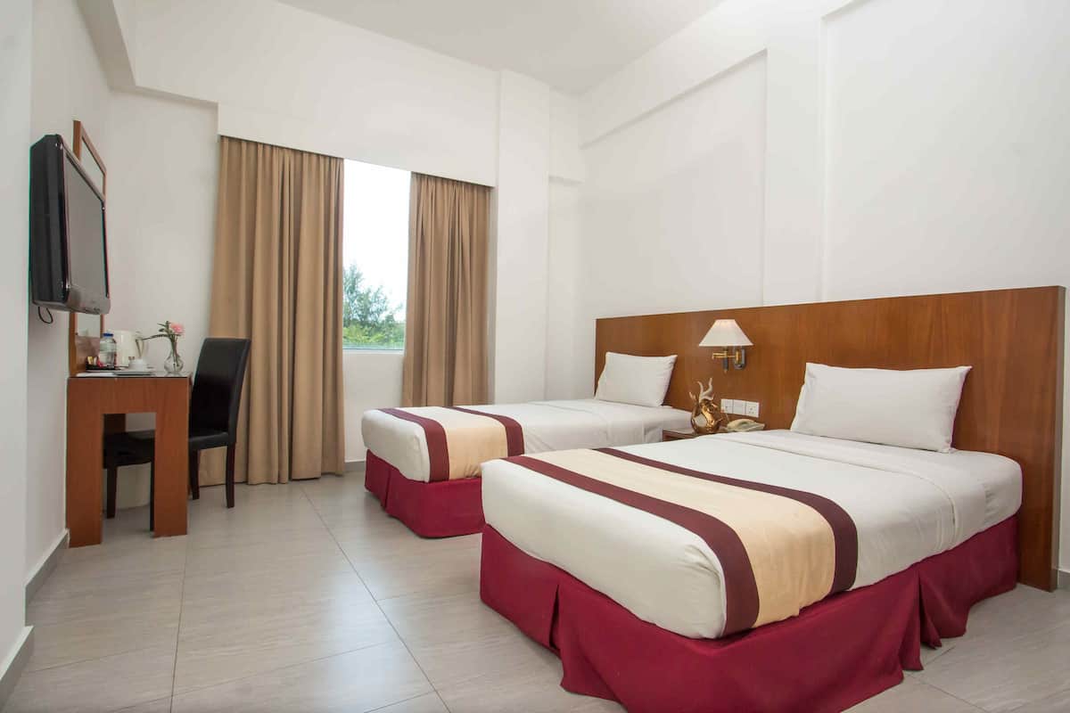 A hotel room with two beds, a desk, a chair, a TV, and a window with curtains.