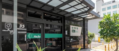 A modern building with a glass entrance, a green 'Hello' sign, and a 'CHECKIN Express' sign.