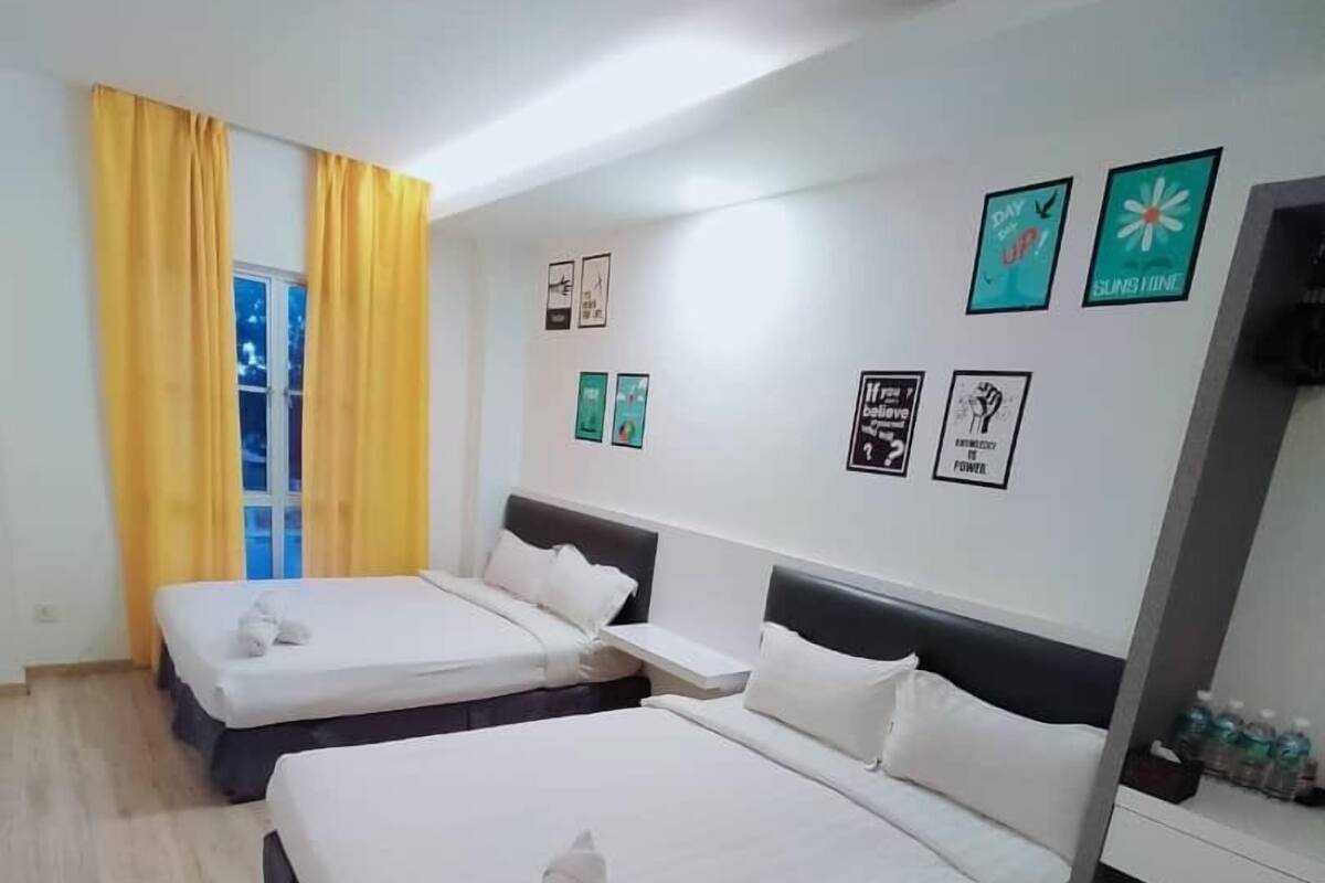 Ein Hotelzimmer mit zwei Betten, einem Fenster mit gelben Vorhängen und Wanddekorationen, darunter Motivationsplakate.