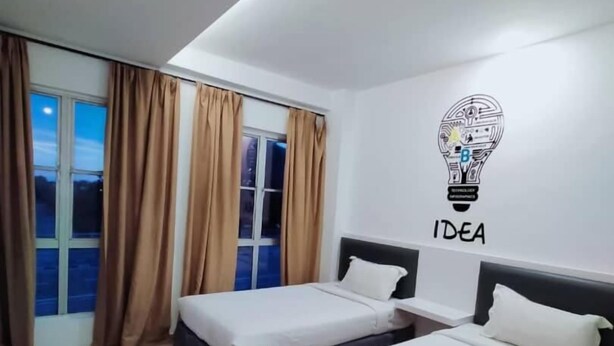 A modern hotel room with two beds, a large window with curtains, and a wall with an 'IDEA' light bulb graphic. - Hotel Zamburger Plaza Mahkota (Malacca City)