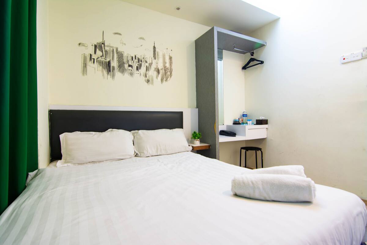Ein Hotelzimmer mit einem großen Bett, einem Nachttisch, einem Spiegel und einem Wandbild.