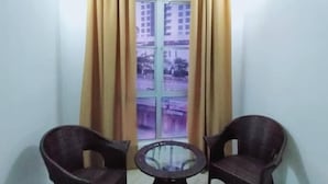 A room with two wicker chairs, a small round table, a ceiling fan, and a window with curtains. - Hotel Zamburger Plaza Mahkota (Malacca City)
