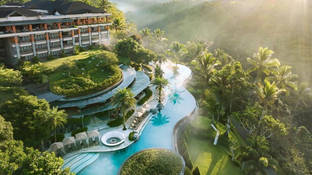A resort with a swimming pool, palm trees, and a building with multiple balconies. - Padma Resort Ubud (Payangan)