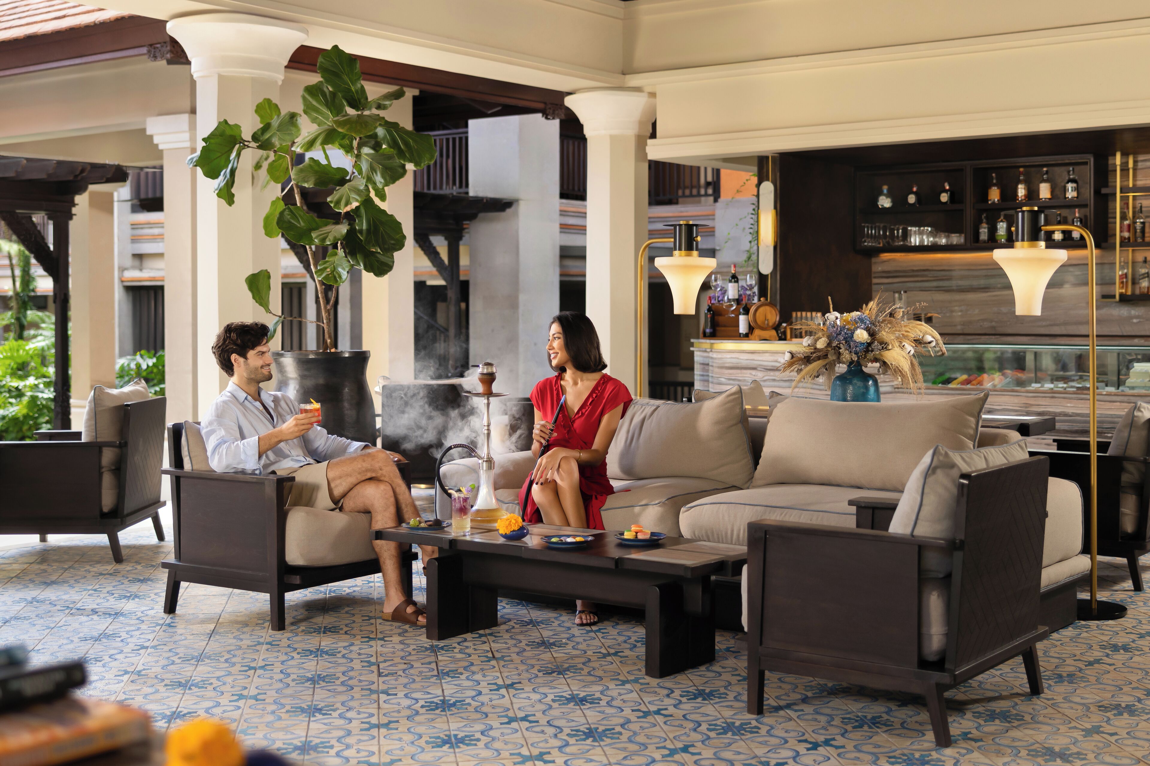 A lounge area with a bar, seating, and a large plant.
