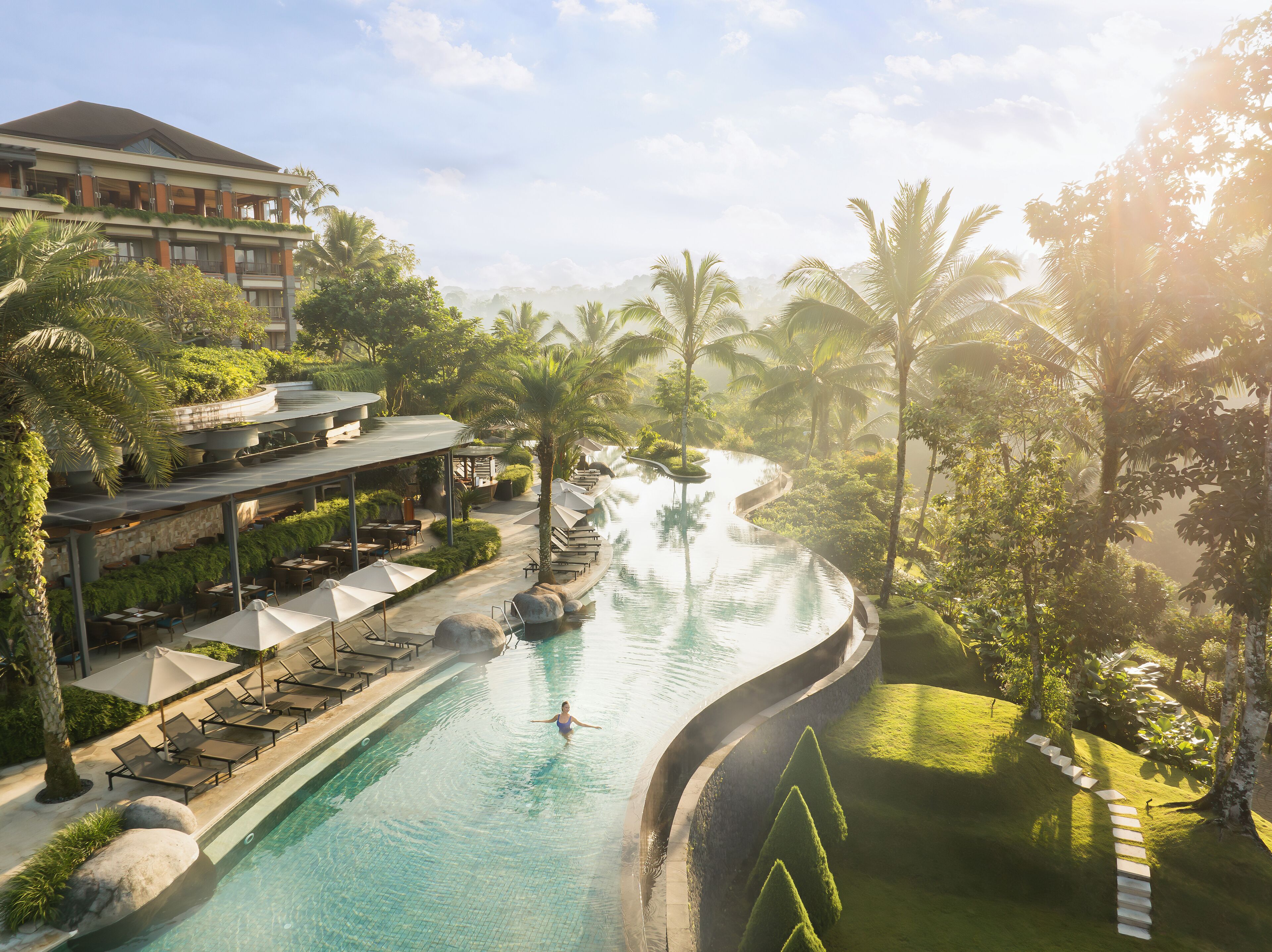 A resort with a swimming pool, lounge chairs, and a restaurant area.