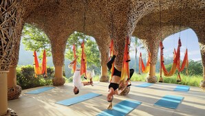 A yoga studio with a natural setting, featuring mats and hammocks for practice. - Padma Resort Ubud (Payangan)