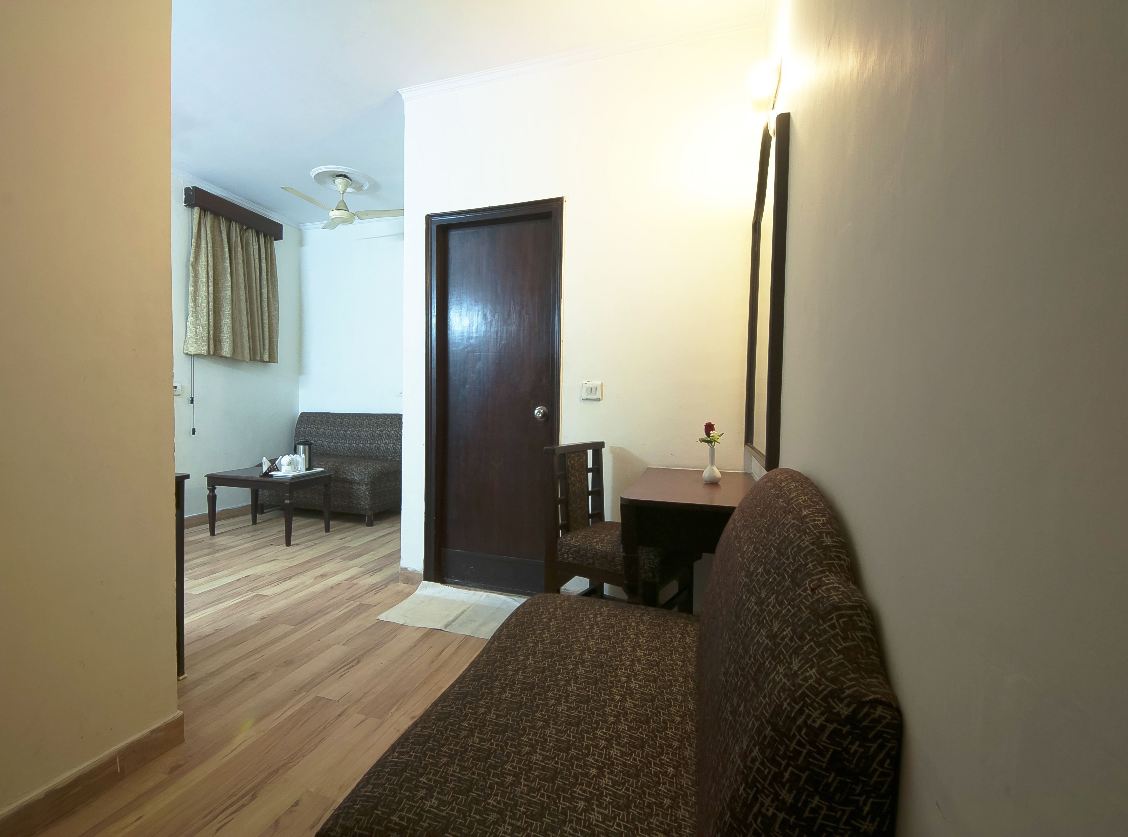 Un salon avec un canapé, une petite table, une porte en bois foncé et un ventilateur de plafond.
