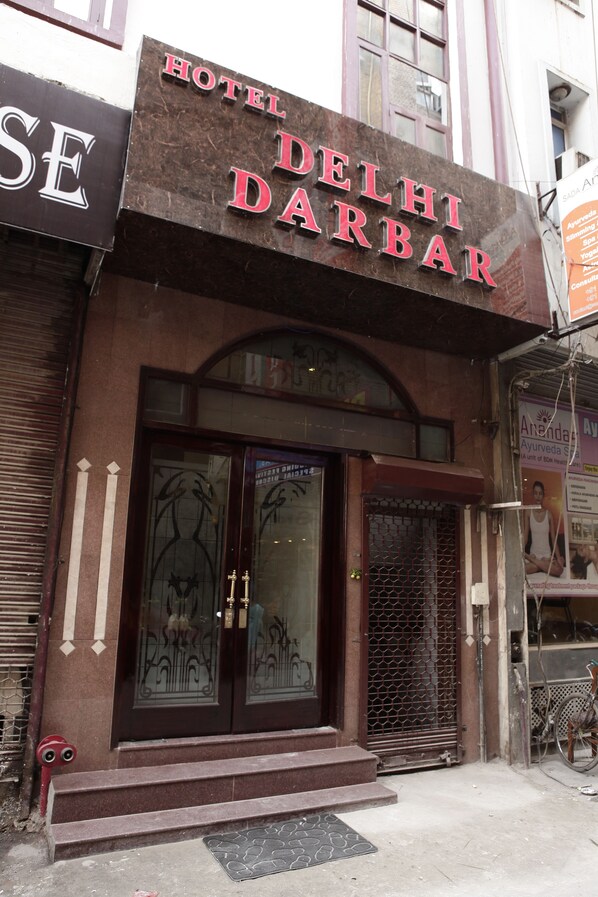 Entrada de un hotel con un cartel que dice 'Hotel Delhi Darbar'.