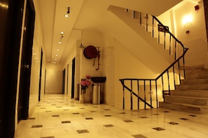Un vestíbulo de hotel con piso a cuadros, una escalera y un radiador fijado a la pared.