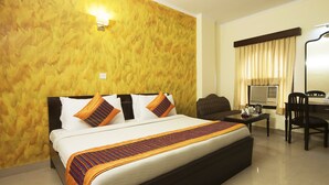 A hotel room with a large bed, a desk with a chair, a television, and a wall-mounted light. - Hotel Delhi Darbar (New Delhi)