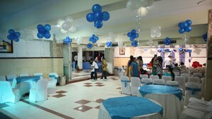 A banquet hall with round tables covered in blue tablecloths, white chairs, and blue and white balloons. - Hotel Ekant (Faridabad)