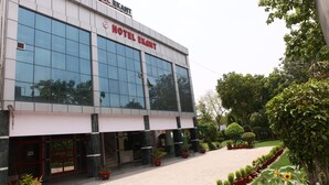 A modern hotel building with a large glass facade, a well-maintained garden with potted plants, and a clear entrance. - Hotel Ekant (Faridabad)