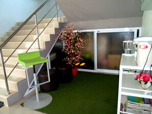 A staircase with a green chair, a potted plant with pink flowers, and a white coffee machine. - Papangkorn House (Surat Thani)