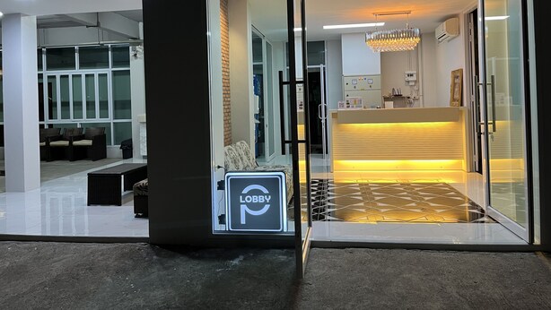 A modern lobby with a reception desk, glass doors, and a chandelier. - Papangkorn House (Surat Thani)