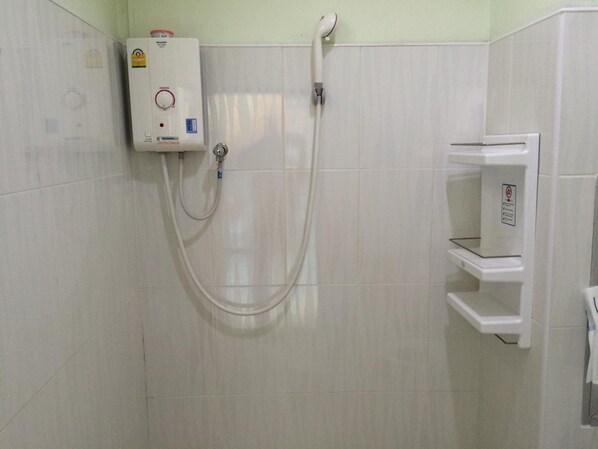 A bathroom with a white shower enclosure, a built-in toilet, and a white towel rack. - Papangkorn House (Surat Thani)