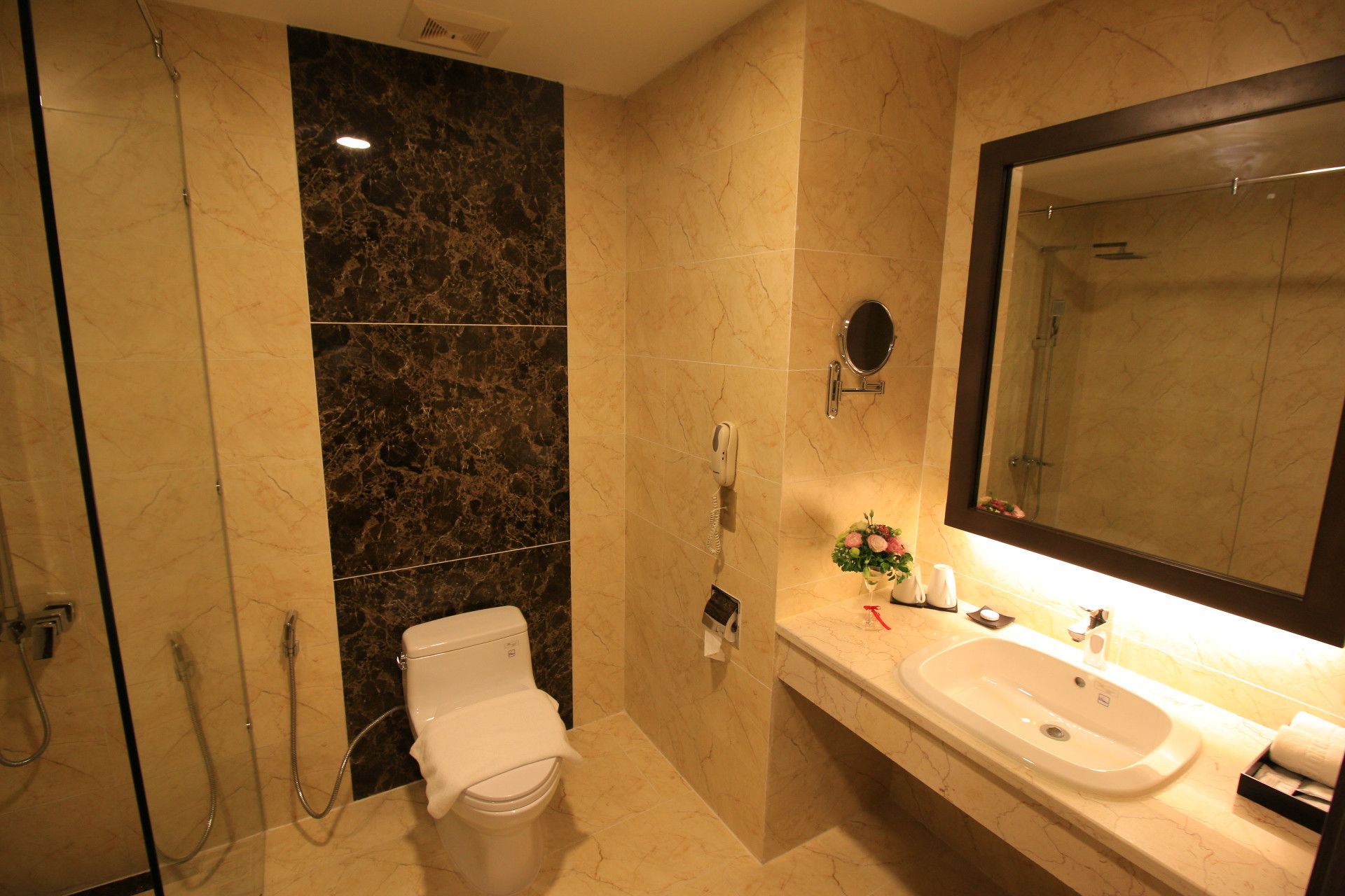 A bathroom with a toilet, a sink, a mirror, and a shower.