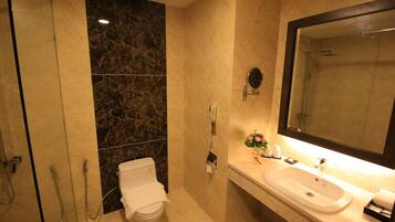 A bathroom with a toilet, a sink, a mirror, and a shower.