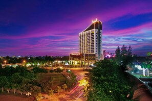 Un hotel moderno de gran altura, rodeado de vegetación y un entorno urbano bien iluminado.