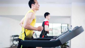 Two individuals running on treadmills in a gym with a window in the background.