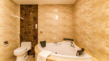 A modern bathroom with a toilet, a bathtub, and marble walls.