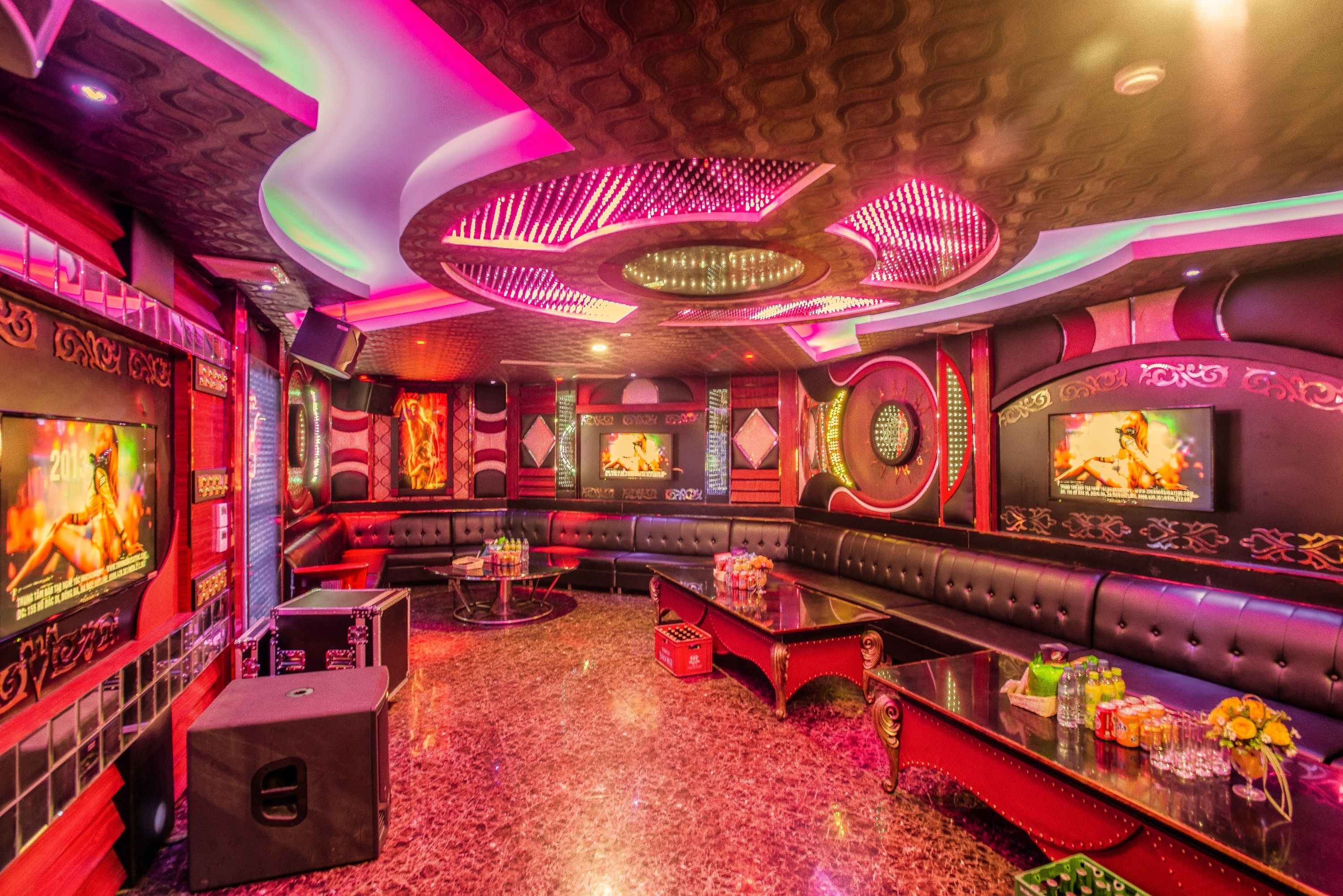 A luxurious lounge area with plush seating, a bar, and a large screen.