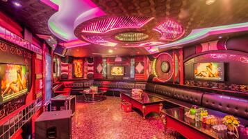 A luxurious lounge area with plush seating, a bar, and a large screen.