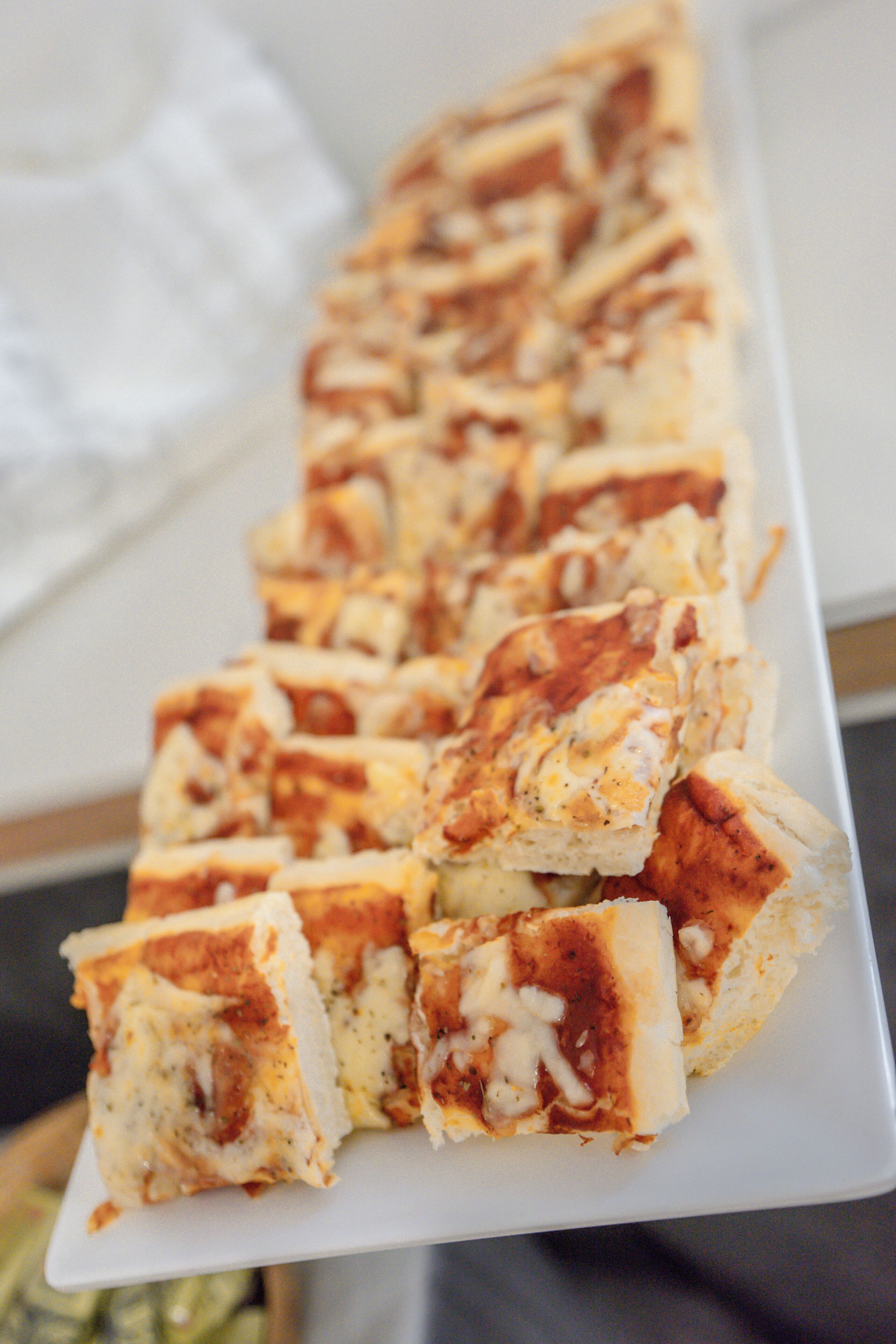 Ein weißer Teller mit verschiedenen Brotscheiben, belegt mit Käse und Kräutern.