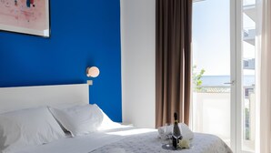 A hotel room with a bed, a bottle of champagne, and a view of the sea. - Hotel Sanremo (Rimini)