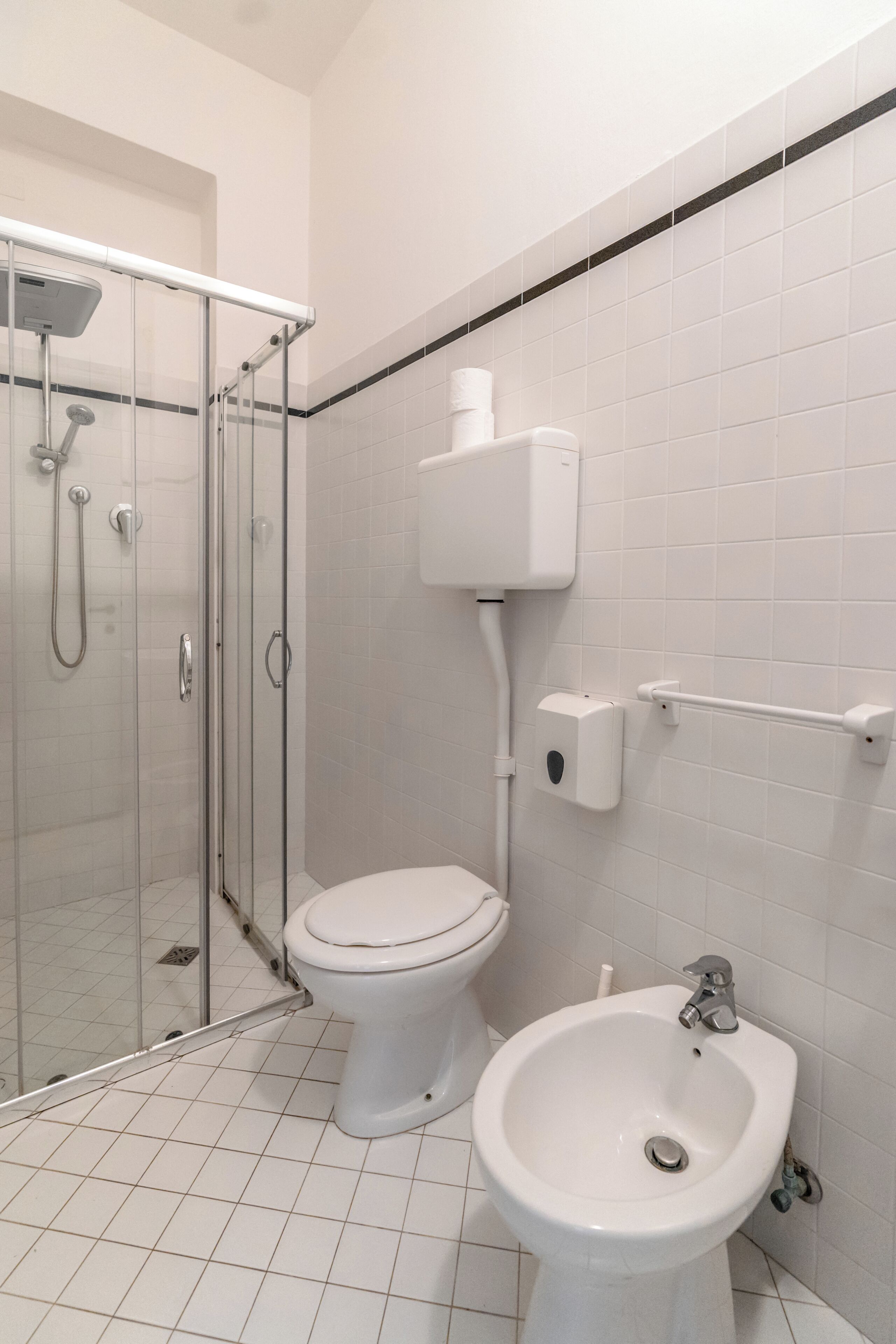 A bathroom with a toilet, bidet, and glass-enclosed shower.